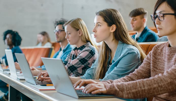 Close Up Of Students in Lecture Hall Using Laptops