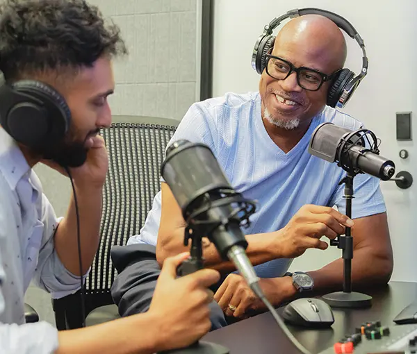 Two people smiling and talking into microphones