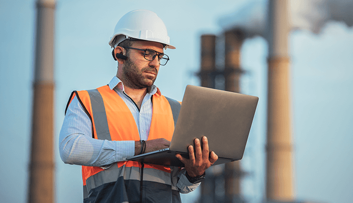 Industrial Man Holding Laptop and Wearing White Hardhat