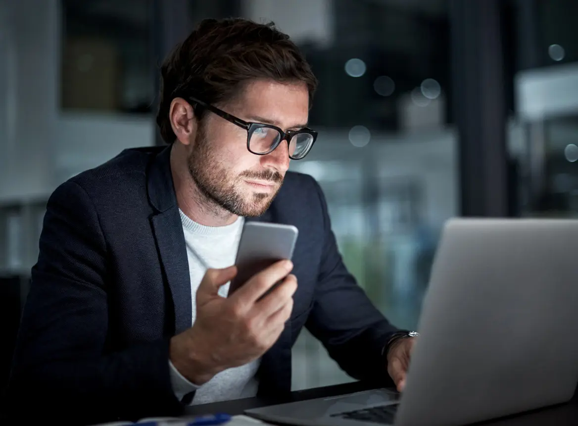 Man Using Laptop and Phone: Global