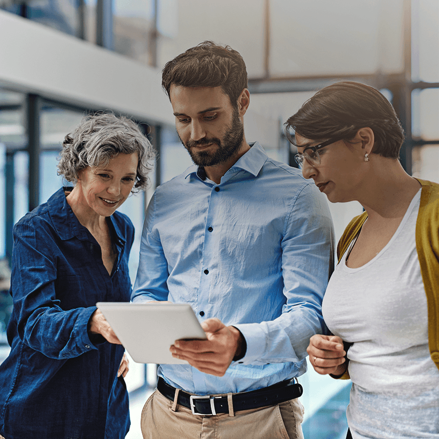 Three People In an Office Looking at a Tablet